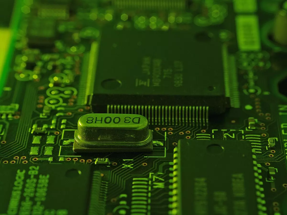 A close-up shot of a green circuit board with a focus on a chip labeled 'D3 00H8'. The image captures the intricate details of the circuit board, showcasing the complexity of semiconductor design.