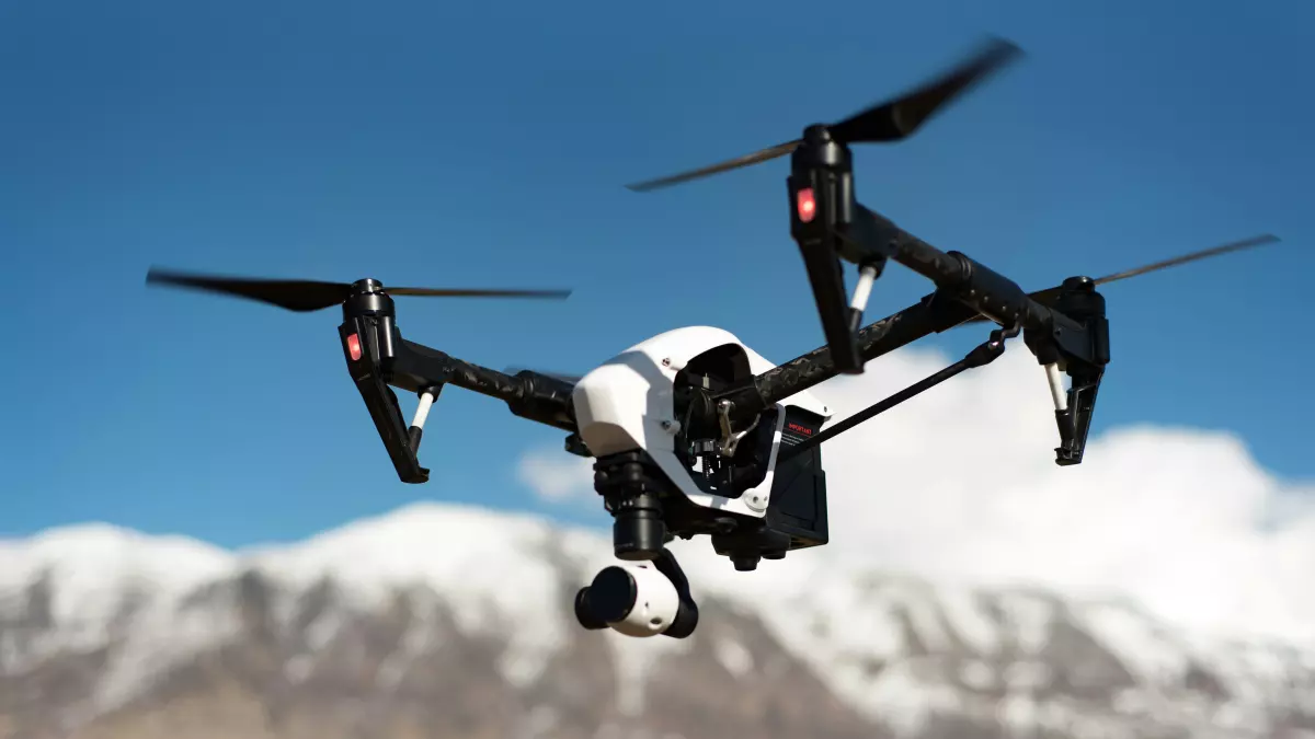 A drone flies over a mountain landscape, showcasing its autonomous navigation capabilities.