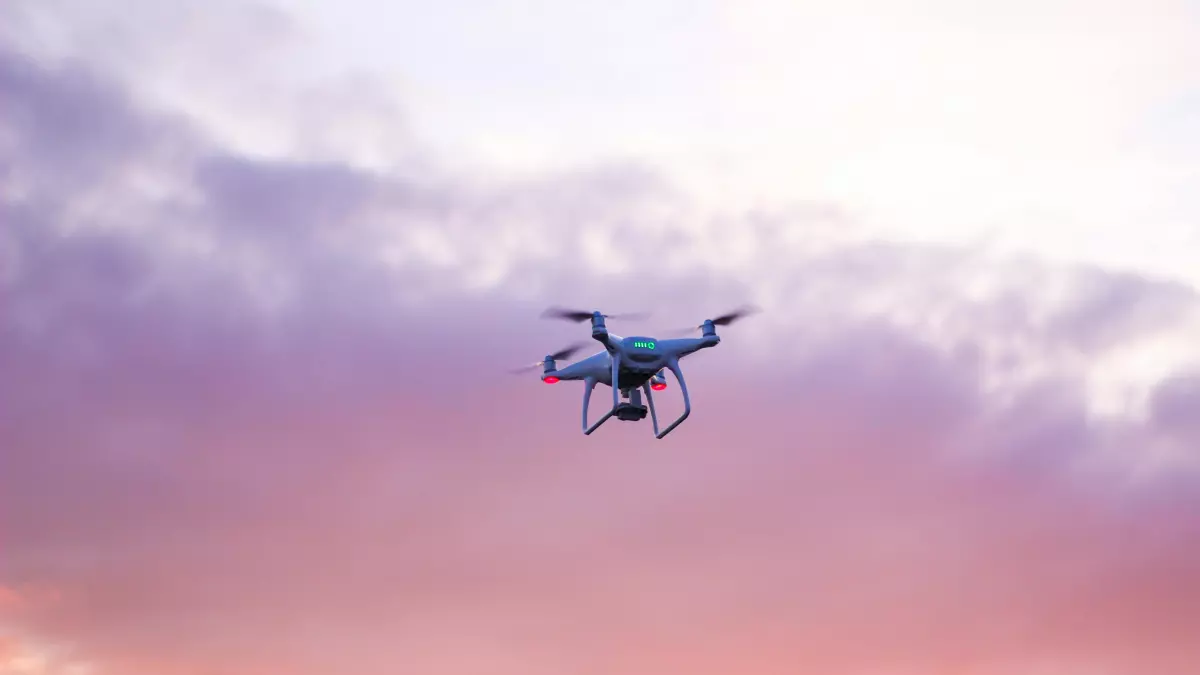 A drone flying in the sky with a cloudy sky and a sunset.