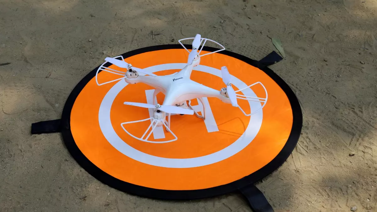 A white drone landing on a designated landing pad. 