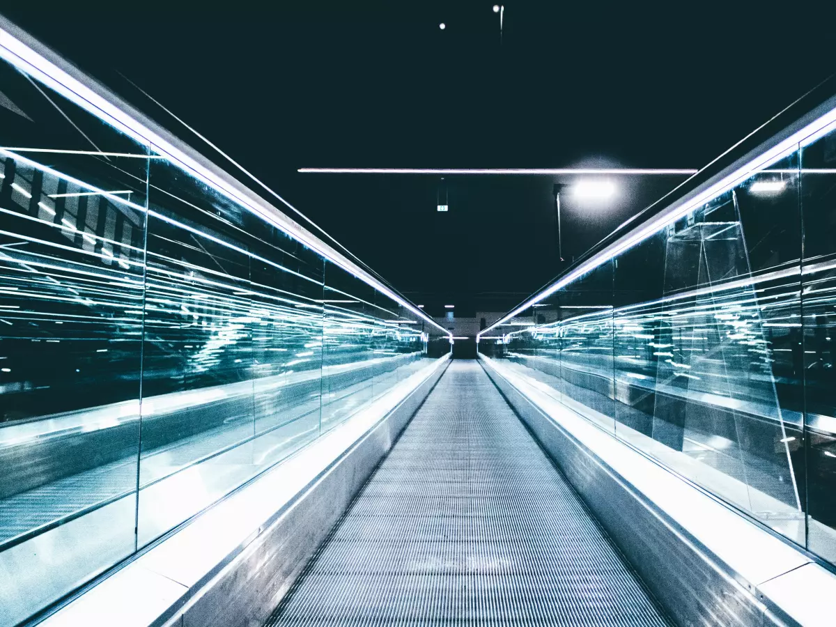 A futuristic escalator leading into the distance. The white lights illuminate the sleek, modern design. 