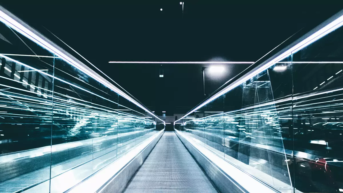 A futuristic escalator leading into the distance. The white lights illuminate the sleek, modern design. 