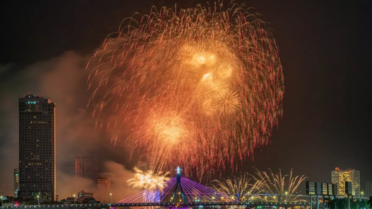 A fireworks display over a bridge in a city at night.