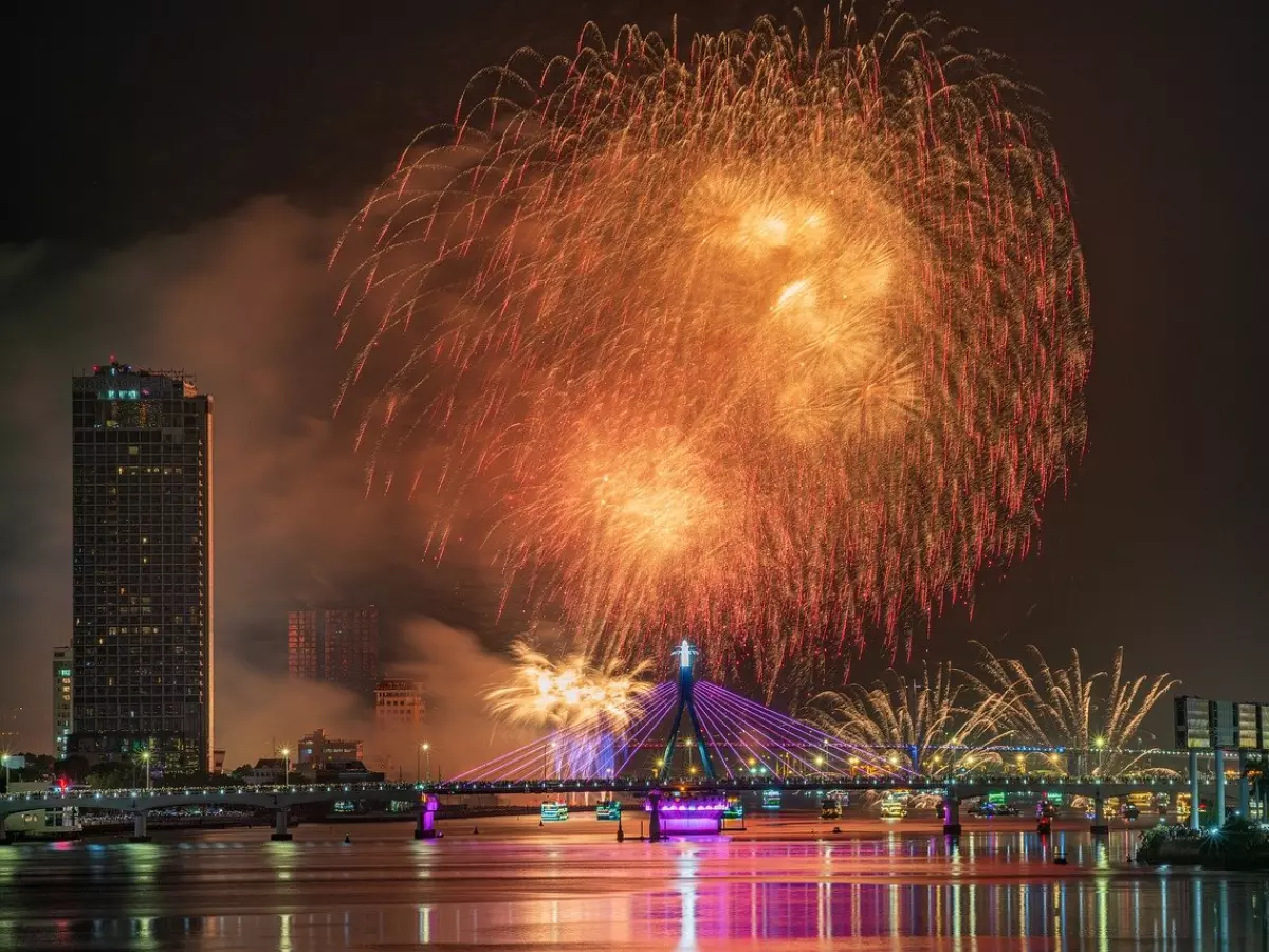 A fireworks display over a bridge in a city at night.