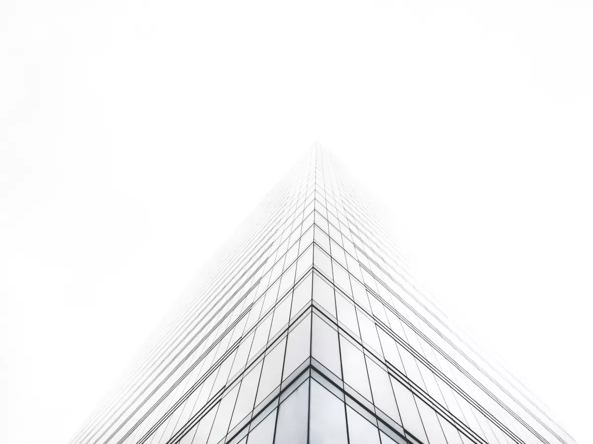 A tall glass building reaching up towards the sky, seen from a low angle.  The building is made of many glass panels.