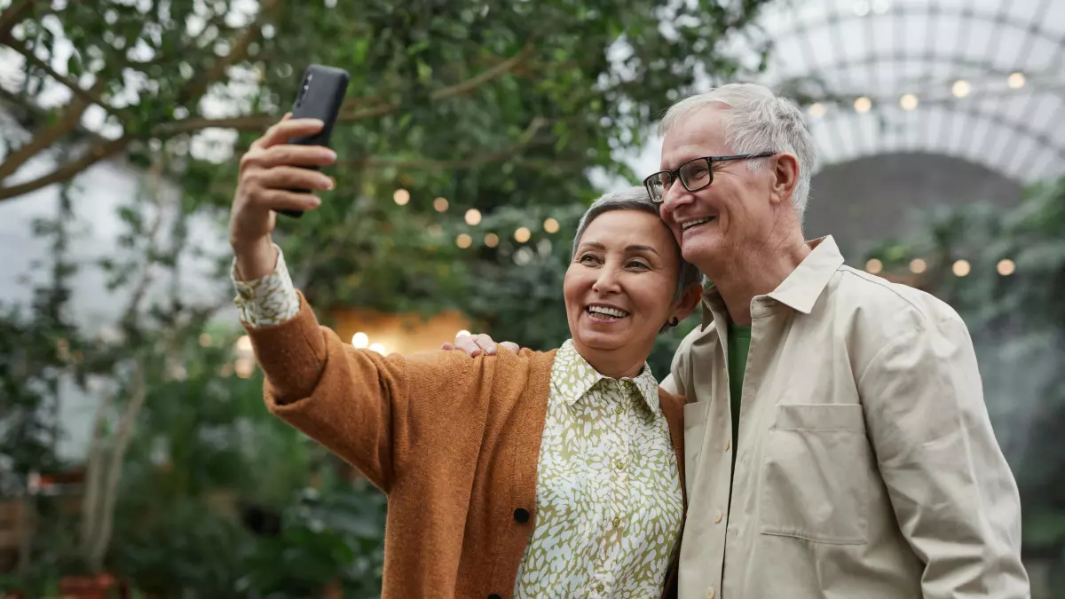 An older couple is taking a selfie in a botanical garden.