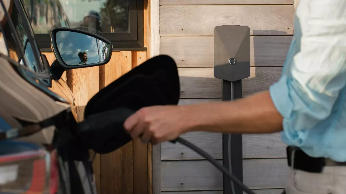 A person plugging in an electric vehicle with a charging cable. 