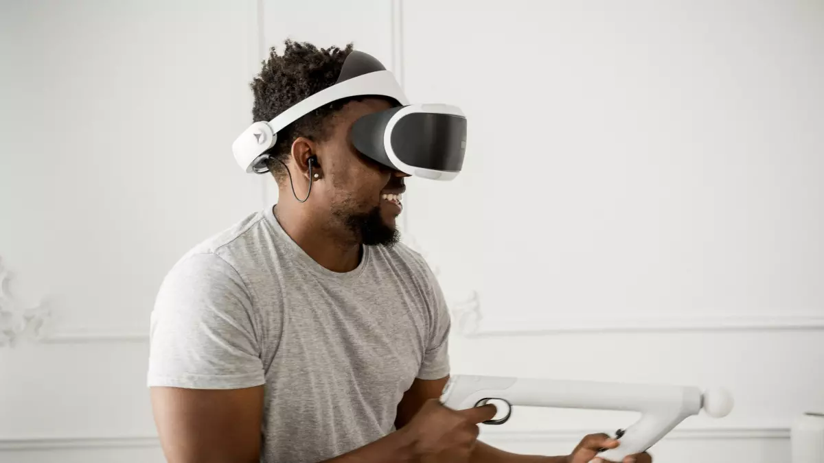 A young man wearing a VR headset and holding two controllers is playing a VR game.