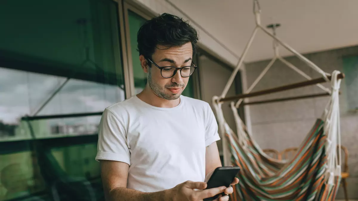 A young man using his smartphone on a balcony