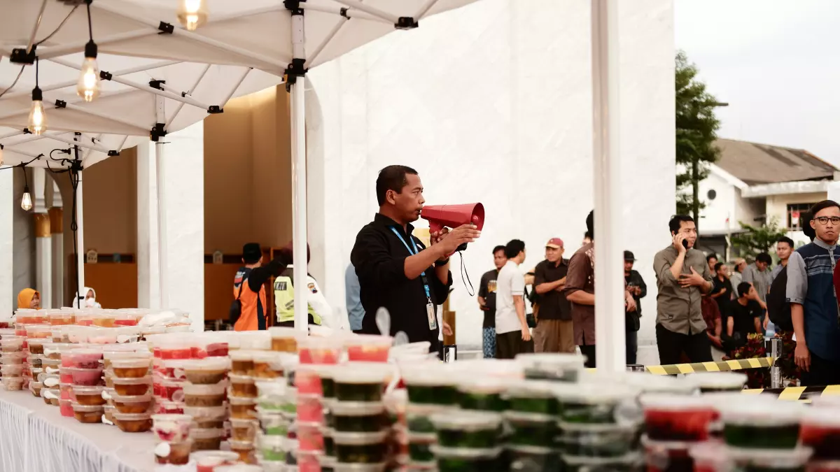 A man speaks into a megaphone at a food stall.