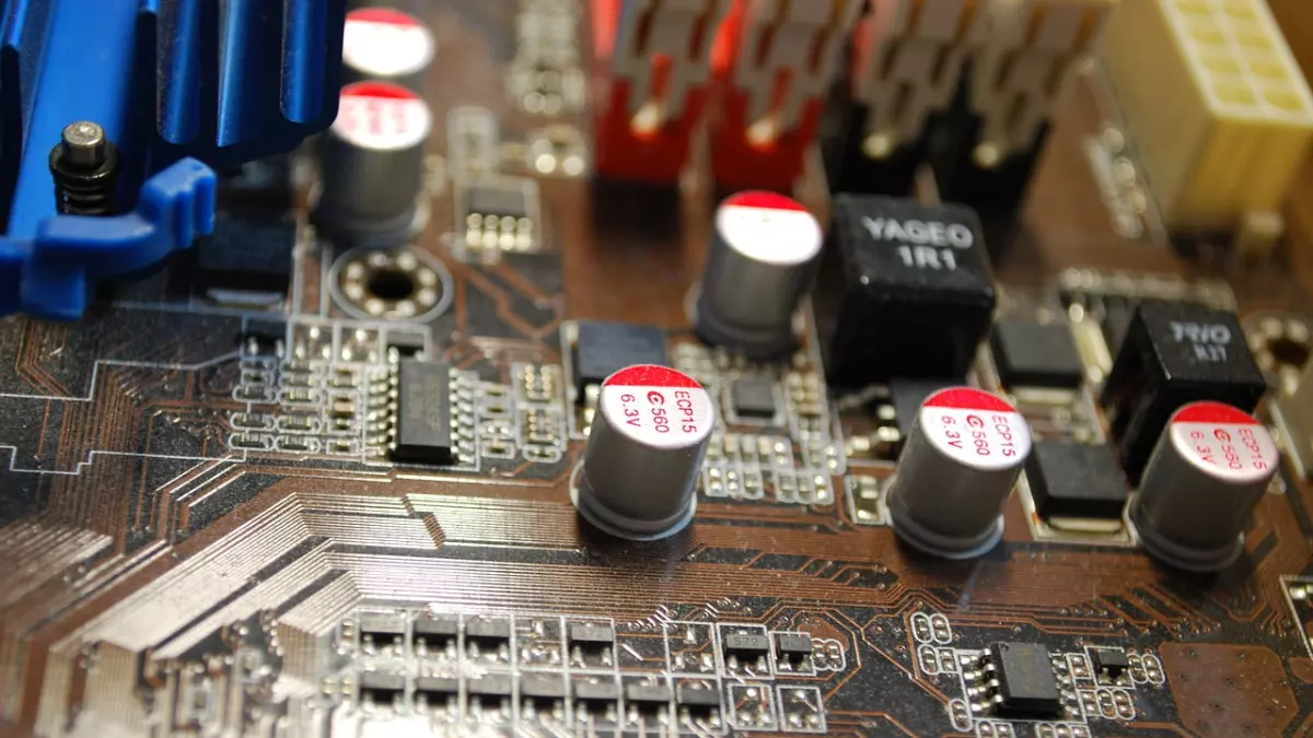 Close-up of a computer motherboard with visible components, including capacitors, integrated circuits, and traces.