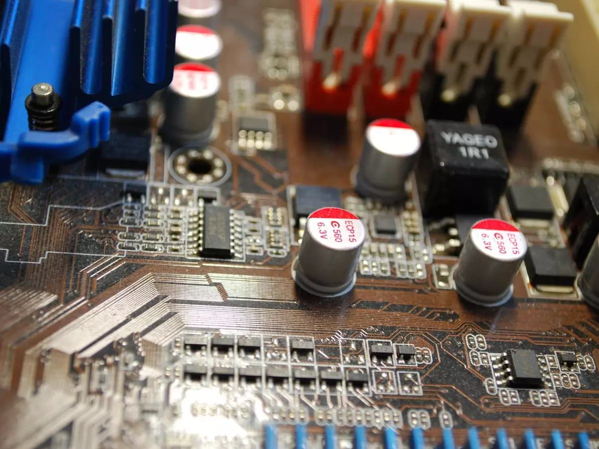 Close-up of a computer motherboard with visible components, including capacitors, integrated circuits, and traces.