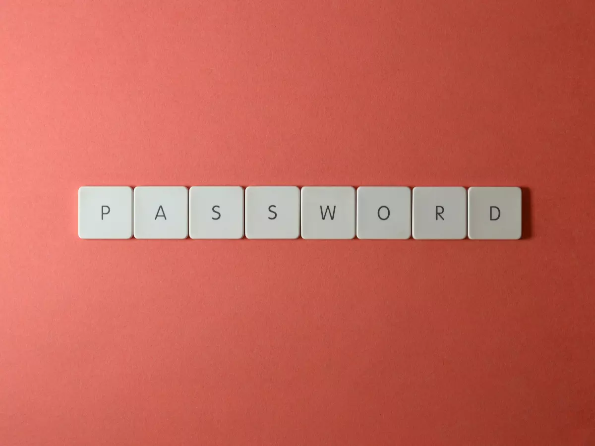 A close-up shot of the word 'PASSWORD' spelled out using individual keyboard keys on a coral background.