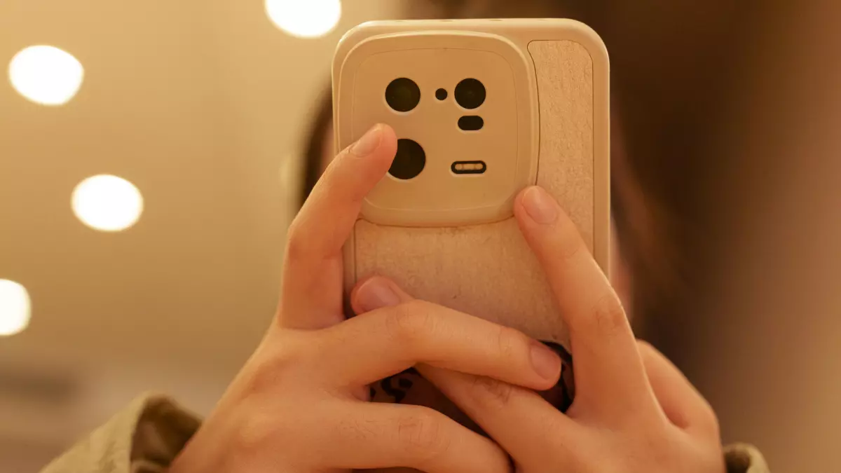 Close-up of hands holding a gold smartphone, focusing on the interaction between the fingers and the phone