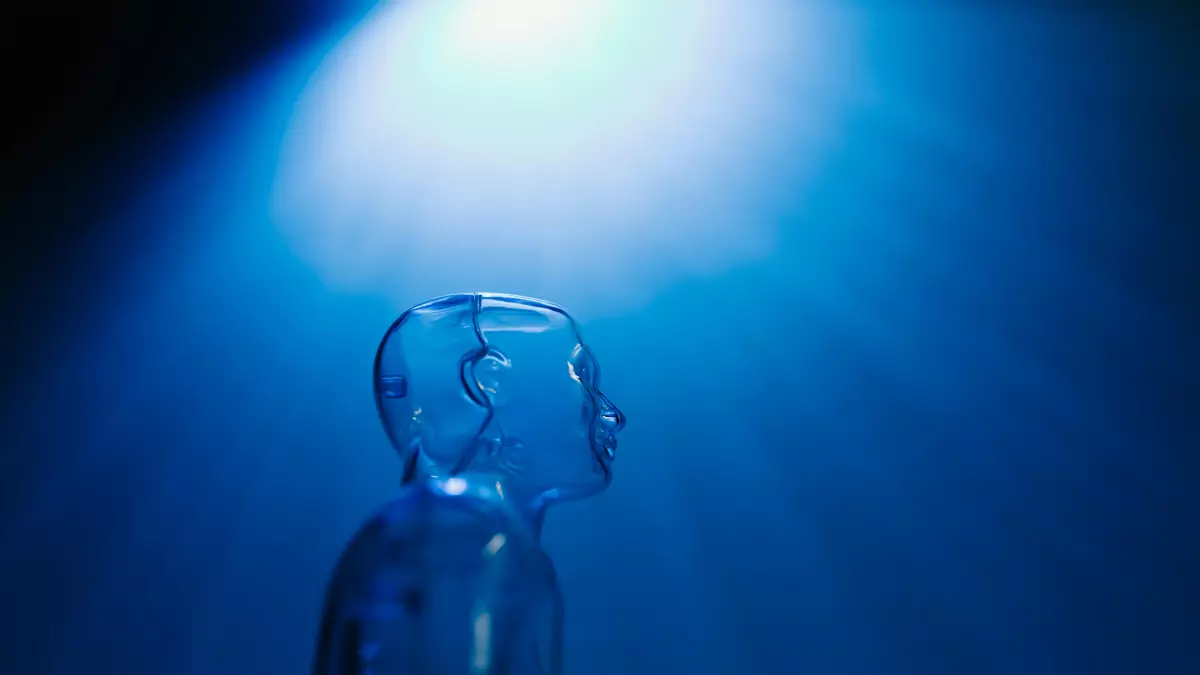 A close-up of a humanoid robot made of clear plastic, with a spotlight shining on its head from the top left. The robot is silhouetted against a blue background. 