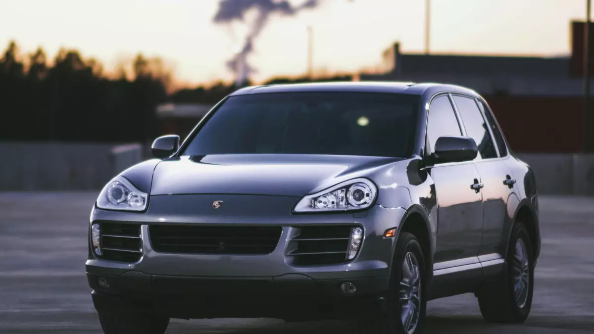 A silver Porsche Cayenne SUV parked in a parking lot at sunset.