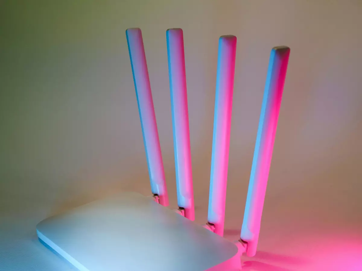 A white router with multiple antennas, illuminated with blue and red light.