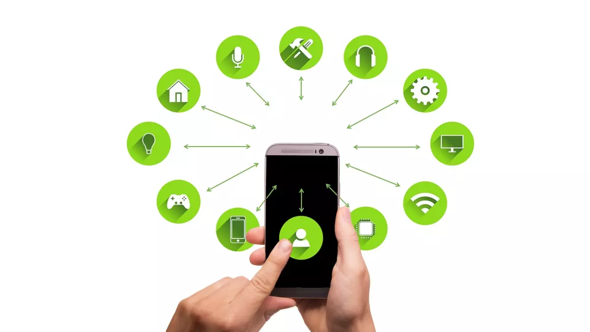 A hand holding a smartphone with various smart home icons displayed around it on a white background.